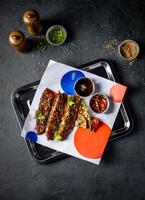 Hickory Bbq Beef Brisket Belly with Dipping Sauces and sesame seeds served in tray isolated on grey background top view of A la carte Food platter photo