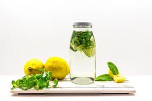 Refreshing Detox Water with Lemon, Lime, and Mint Classic Mojito served in bottle isolated on wooden board side view of cold beverage on white background photo