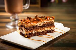 Decadent Chocolate Caramel Layer Cake with Drizzle Chocolate Sauce and Hot Chocolate Coffee mug served in tray dish isolated on table side view of cafe baked dessert food photo