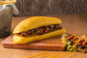 Cheesesteak Sandwich with Fries and Salad isolated on wooden board side view of fast food on table photo