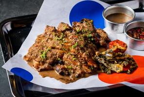 Spicy Grilled Jerk Chicken Slice with Sweet and Sour Sauce, sesame seeds and tomato served in tray isolated on grey background closeup side view of A la carte Food platter photo
