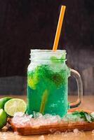 MOCKTAIL MOJITO with Refreshing Mint Lemonade with Lime and Ice served in jar with straw isolated on wooden board side view of perfect drink for a hot summer day photo
