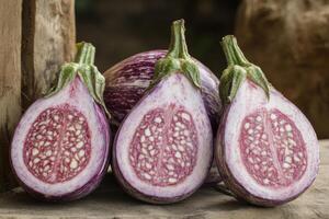 Freshly cut heirloom eggplants revealing vibrant purple flesh with intricate seed patterns on a rustic wooden surface photo