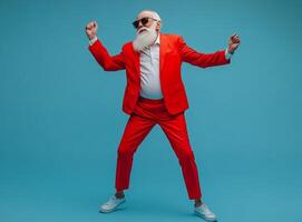 A photo of an elderly dancing man with a gray beard in a red suit on a blue background. The concept of a New Year's holiday, a birthday.