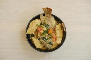Fried fish with curry in a bowl on a wooden table. photo