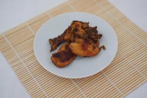 Fried chicken on a white plate with a bamboo mat photo