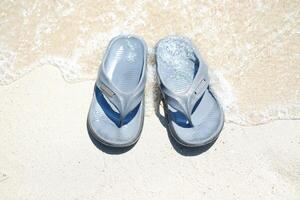 flip flops on the sand at the beach with sea background photo