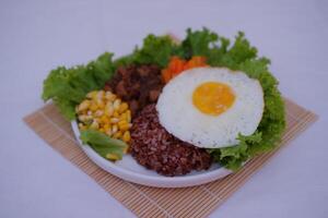 Red rice with fried egg and vegetables on white background. photo