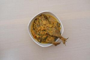 Fried fish with curry in a bowl on a wooden table. photo