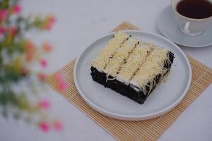 A piece of black cake topped with shredded cheese photo