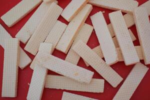 beige wafer cookies with a cream filling is scattered on a bright red surface photo