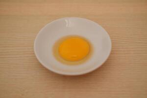 Egg yolk in a white bowl on wooden table background. photo