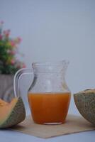 Melon juice in a glass and fresh melon on the table photo