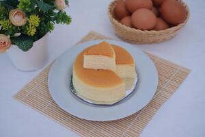 Cheesecake on white plate with flower and eggs in background. photo