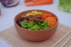 Salad with carrot, corn and lettuce in a clay bowl. photo