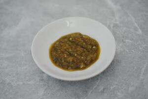 green sambal in a white bowl on a marble table. photo