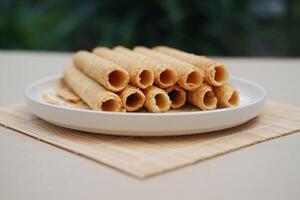 Pile of Cigarette Russe rolled biscuits on white plate on wooden table. photo