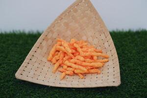 Crispy Corn Puffs in rattan on green grass. Selective focus. photo