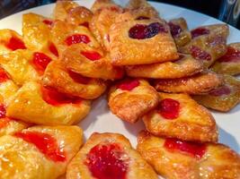 Closeup and crop Homemade Danish pastry yeasted dough with Strawberry Jam on white ceramic plate sell on bakery shop. photo