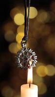 A candle is lit with a silver pendant hanging from it video