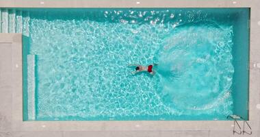 Aerial view as a man dives into the pool and swims. video