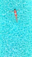 Top down view of a woman in pink swimsuit lying on her back in the pool. video