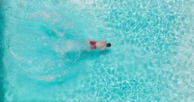 Aerial view as a man dives into the pool and swims. Slow motion video