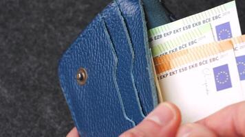 A closeup view of cash being stored in a blue wallet for financial purposes video