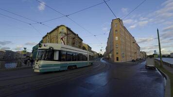 A modern tram glides along a nearly empty street in the early morning light. The surrounding historical buildings are bathed in soft sunlight, creating a tranquil urban scene with clear blue skies video
