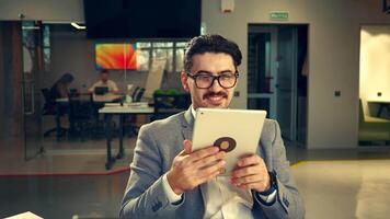 Business professional using a tablet in a modern office environment while collaborating with colleagues in the background video