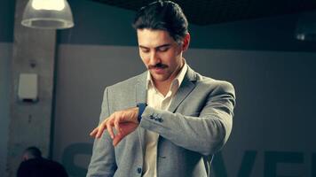 A man in a gray suit reflects thoughtfully while adjusting his cufflinks in an elegant urban setting video