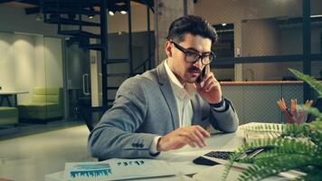 uomo d'affari Lavorando in ritardo a ufficio, analizzando dati, fabbricazione chiamate, e utilizzando calcolatrice per finanziario pianificazione video