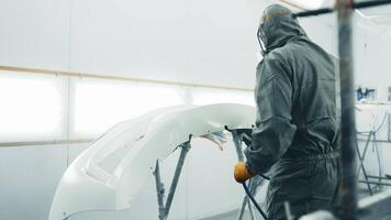 Techniques for spray painting a car bumper in a professional workshop setting video