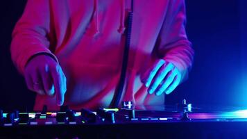 DJ mixes tracks in vibrant light setting during an electrifying live performance at a local music venue video