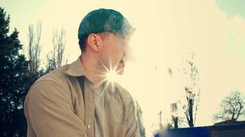 Young man enjoys vaping outdoors during sunset while relaxing in a serene environment video
