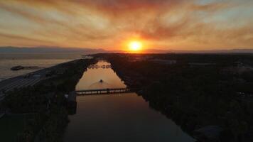 radiante céu pôr do sol sobre a rio e mar com deslumbrante montanha Visão video