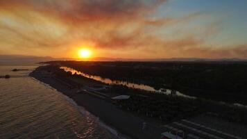 tirar o fôlego pôr do sol zangão Visão do rio fusão com mar atrás exuberante montanhas video