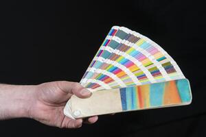 Close-up of hand holding a fanned out color guide photo