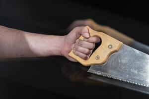 Close-up of man's hand holding a carpentry saw with motion effect photo