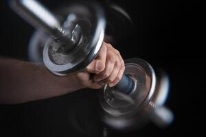 Close up of man's hand exercising with heavy dumbbell with motion effect photo