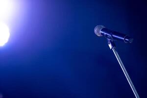 Close-up the microphone on stand for speaker speech at seminar room with blue light background and blur bokeh, Presentation microphone on a stand, Copy space photo