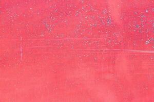 The texture of a pink surface with splashes of blue. A wall or other surface is scuffed and lightly scratched, painted a bright pink, with visible signs of wear and aging photo
