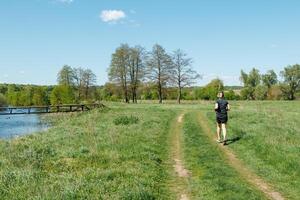 Young fitness woman running on a path near the river to keep fit. A runner trains in the midst of beautiful nature. photo