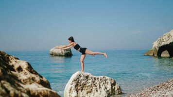 A Woman is Balancing Elegantly on a Rock by the Beautiful and Calm Ocean Waves video