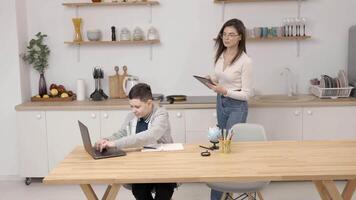 A young woman helps a boy with his lessons using a tablet and a globe. A homeschooling student does his homework with the help of a tutor video