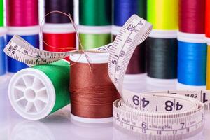 Sewing supplies with colorful thread and measuring tape photo