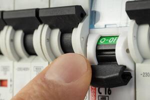 Hand flipping electrical switch in breaker panel photo