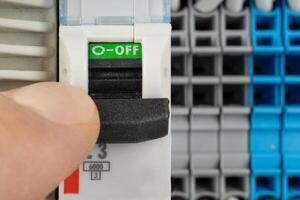 Hand switching off electrical circuit breaker in panel photo