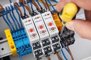 Electrician Adjusting Timer Relay in Control Panel photo