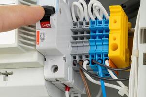 Hand turning on electrical circuit breaker in panel photo